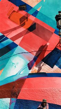 man sitting on wall with artwork and lamp wallpaper