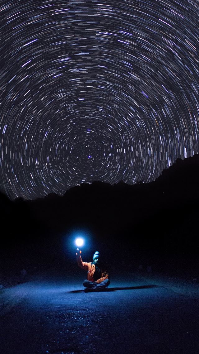 1284x2778 photo of person sitting on pave road holding light - galaxy iPhone Wallpaper