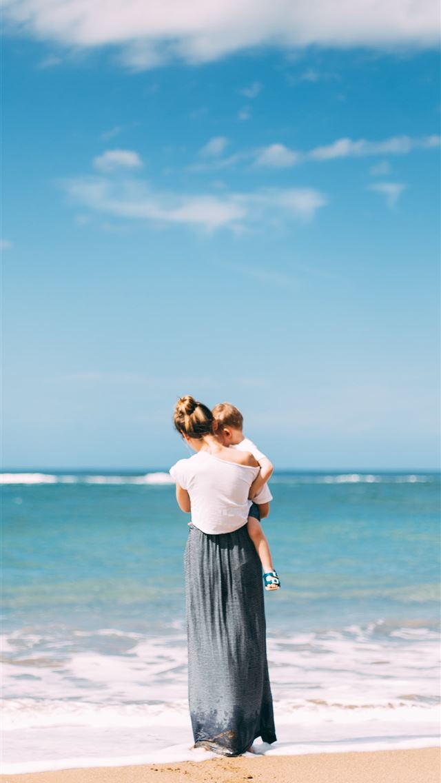 1284x2778 woman carrying toddler on seashore - spain iPhone Wallpaper