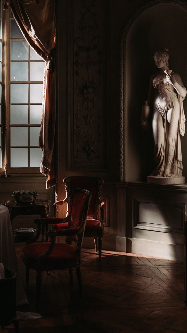 1284x2778 chair beside table beside statue - dark (black) iPhone Wallpaper