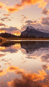 body of water near mountain under cloudy sky durin... wallpaper