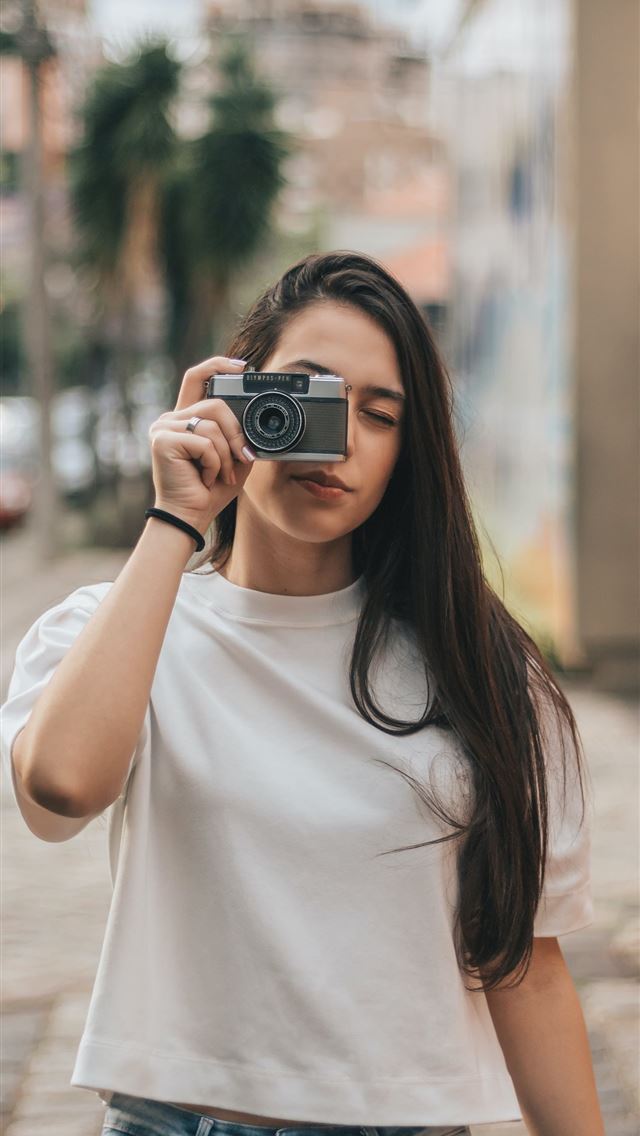 1284x2778 woman holding black and gray bridge camera - brasil iPhone Wallpaper