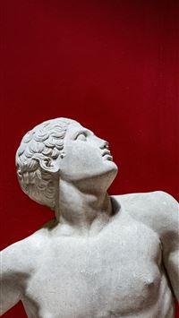 Grecian male statue looks up on red background wallpaper