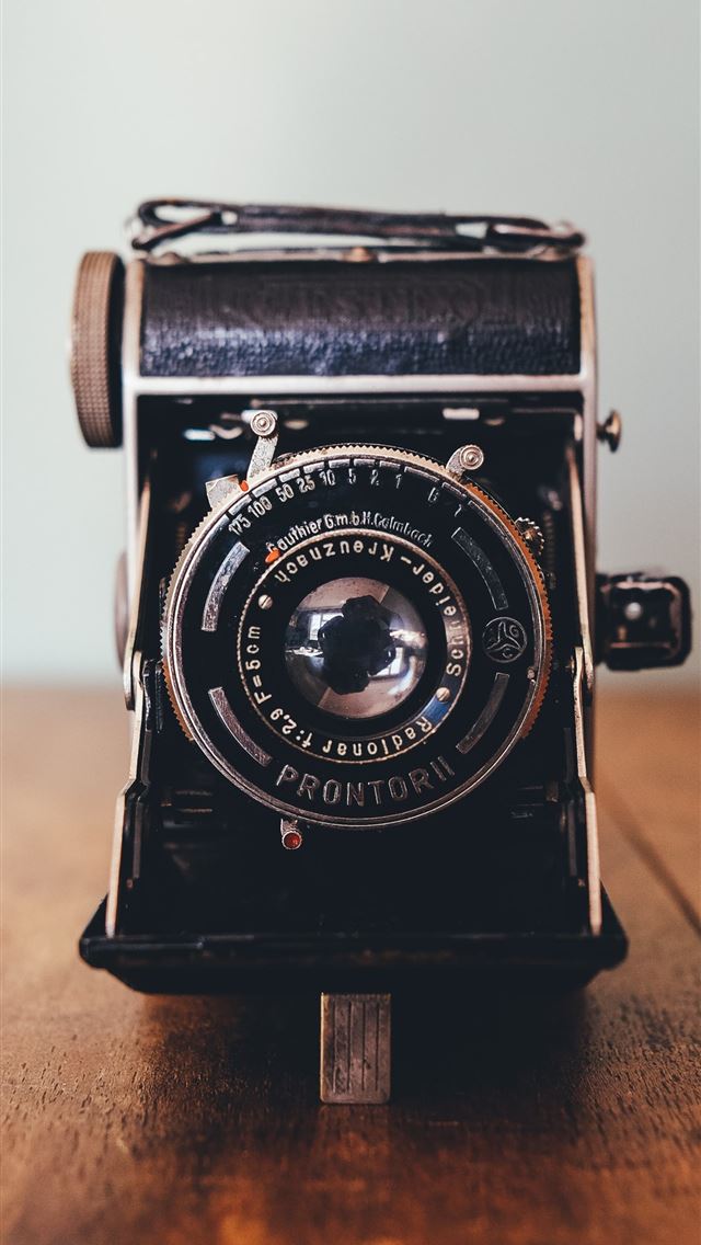 1284x2778 black Prontor II camera on brown wooden board - retro iPhone Wallpaper