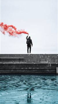 standing man holding lighted flare during daytime wallpaper