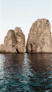two beige rock formations on body of water wallpaper