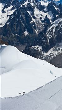 aerial view of two people hiking up snowy mountain wallpaper