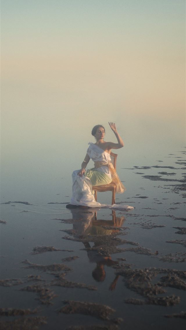1284x2778 woman in white dress sitting on brown wooden chair... - clean iPhone Wallpaper