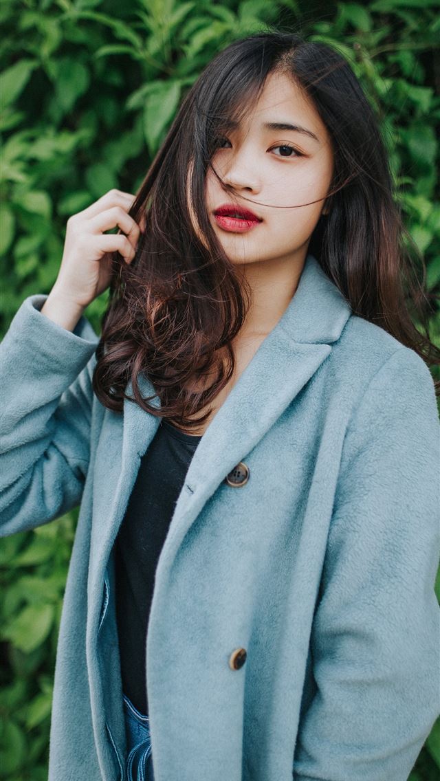 1284x2778 woman in gray coat standing near green plants -  iphone 13 Wallpaper