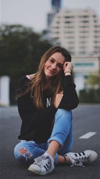woman smiling while sitting on road with hand rest... wallpaper