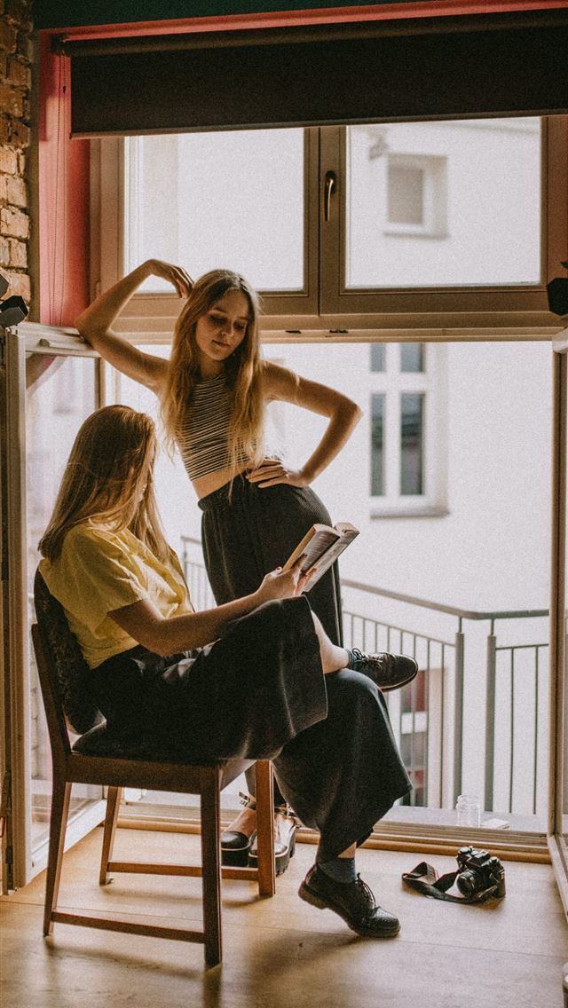 1290x2796 woman standing beside another woman sitting on cha... -  iphone 14 Wallpaper