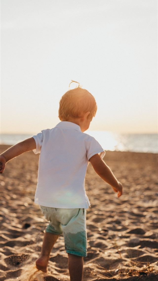 1290x2796 boy standing on sand near sea - sunshine iPhone Wallpaper
