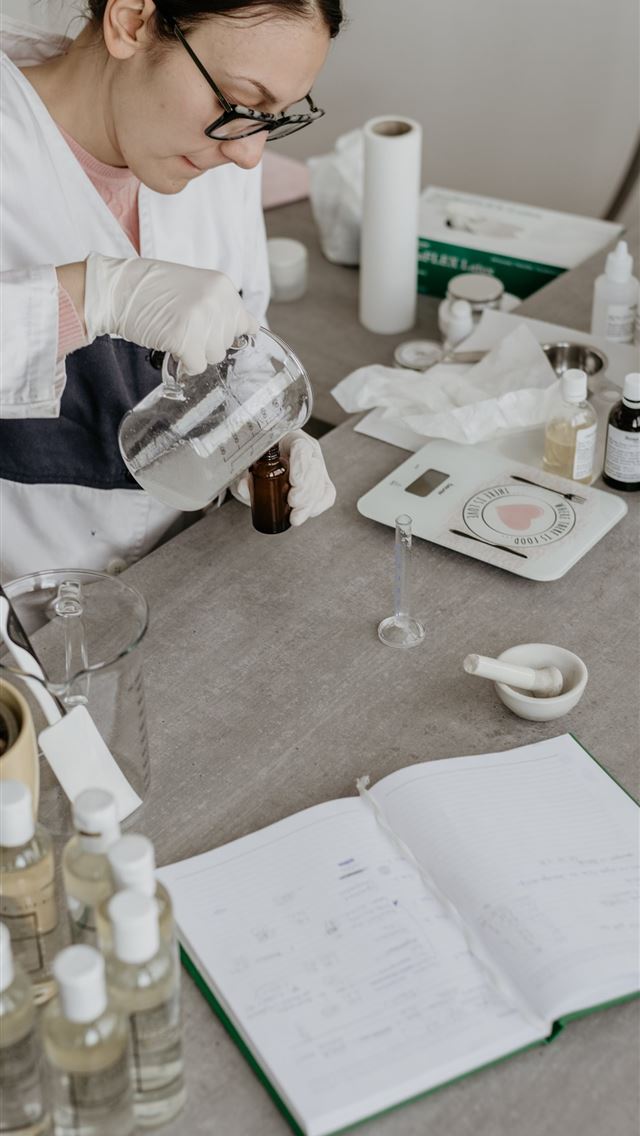 1290x2796 woman mixing liquids while sitting near table -  iphone 14 Wallpaper