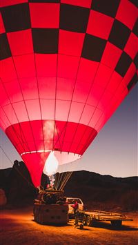 red and black hot air balloon on ground wallpaper