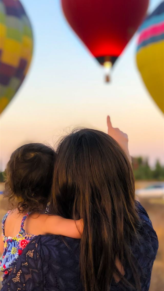 1290x2796 woman carrying toddler point at hot air balloon - colors iPhone Wallpaper