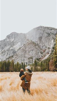 person standing on grass field while carrying chil... wallpaper