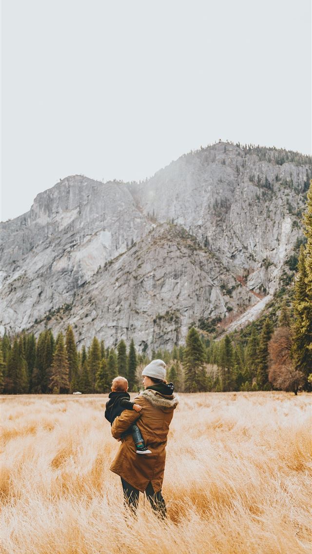 1290x2796 person standing on grass field while carrying chil... - trees iPhone Wallpaper