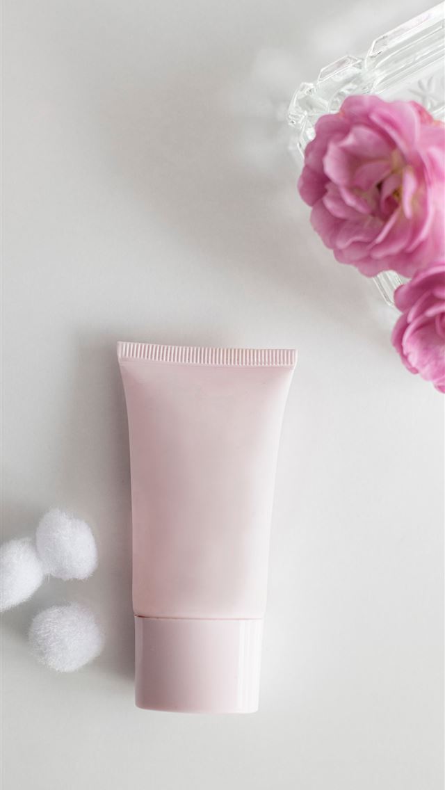 1290x2796 a tube of cream next to a pink flower - beauty iPhone Wallpaper