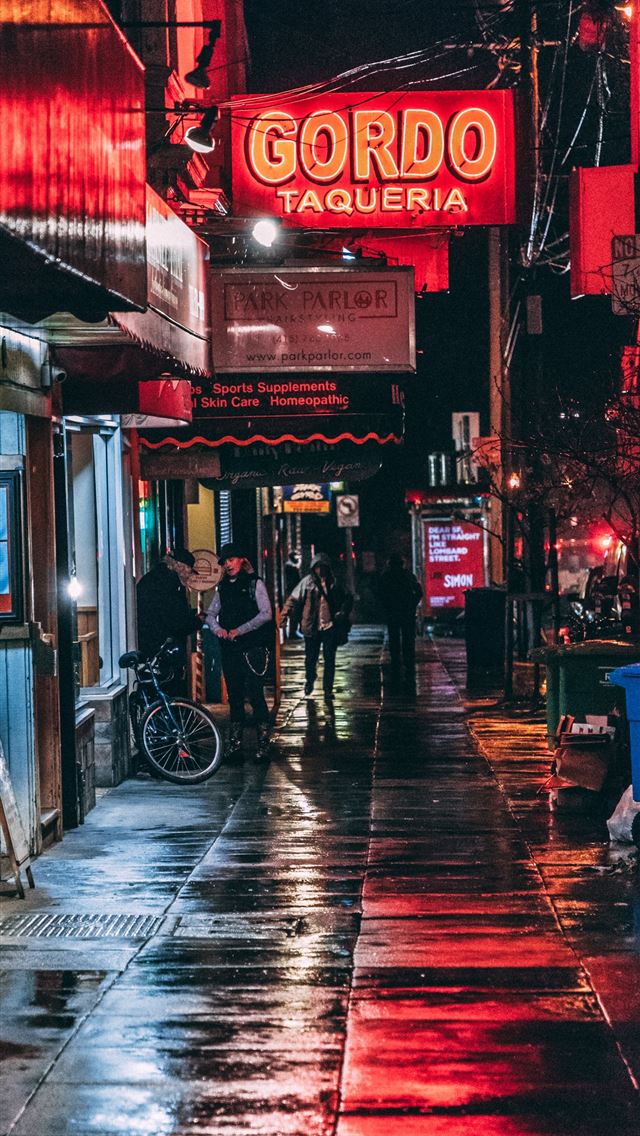 1290x2796 man standing beside store facade - lights iPhone Wallpaper