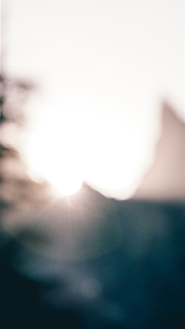 640x1136 a blurry photo of the sun setting behind a buildin... -  iPhone Wallpaper