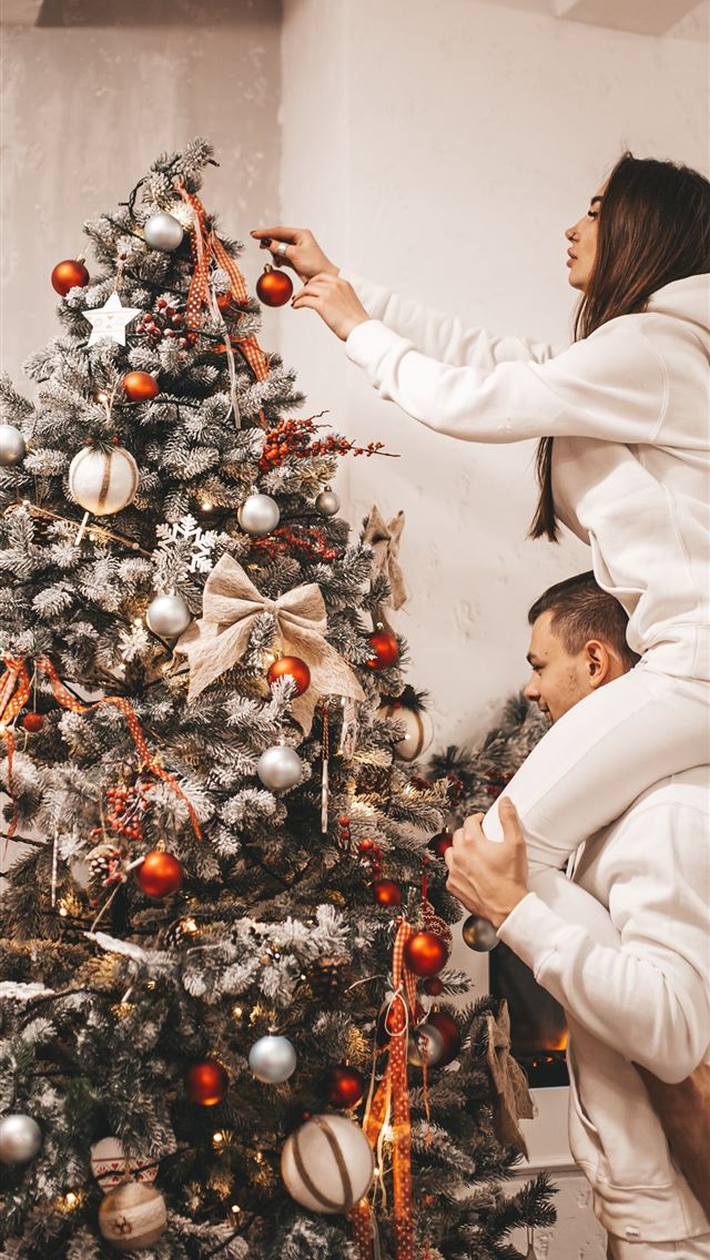 1290x2796 woman putting bauble on Christmas tree - christmas iPhone Wallpaper