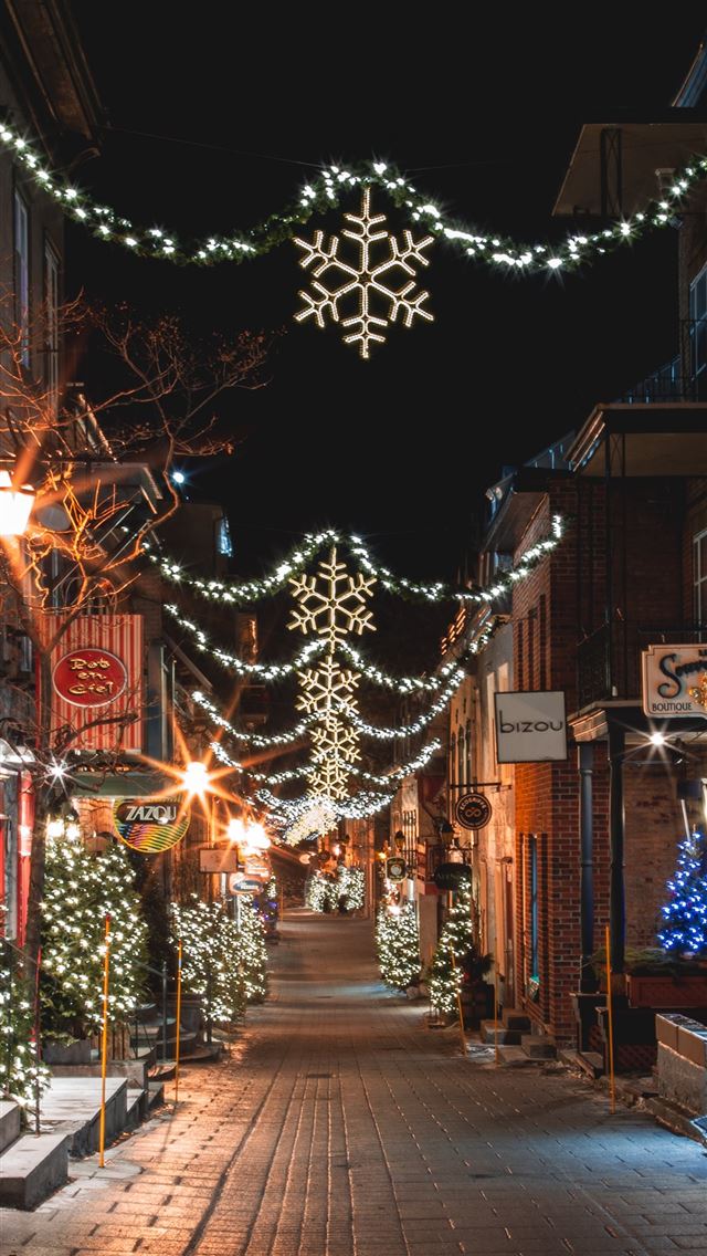1290x2796 a city street is decorated with christmas lights - tree iPhone Wallpaper