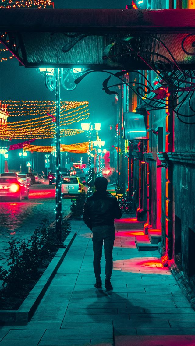 1290x2796 man walking along a sidewalk during nighttime - christmas iPhone Wallpaper