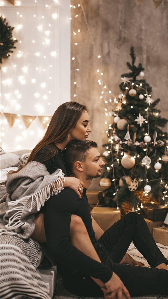 1290x2796 couple sitting beside Christmas tree -  iphone 15 Wallpaper
