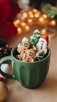 a cup filled with christmas cookies on top of a ta... wallpaper