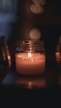 lighted candle in clear glass jar wallpaper