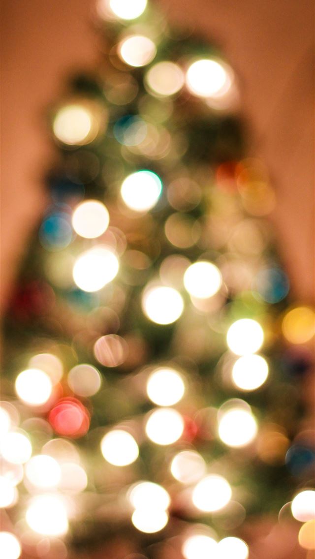 1290x2796 a lit christmas tree in a living room - happy holidays iPhone Wallpaper