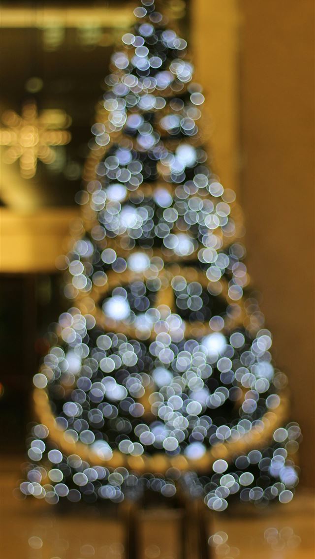 1290x2796 a lit up christmas tree in front of a building -  iphone 15 Wallpaper