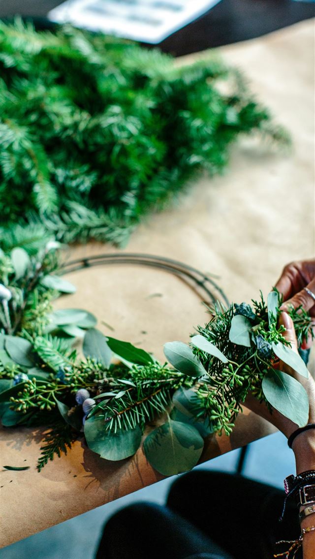1290x2796 woman making green floral wreath on table - person iPhone Wallpaper