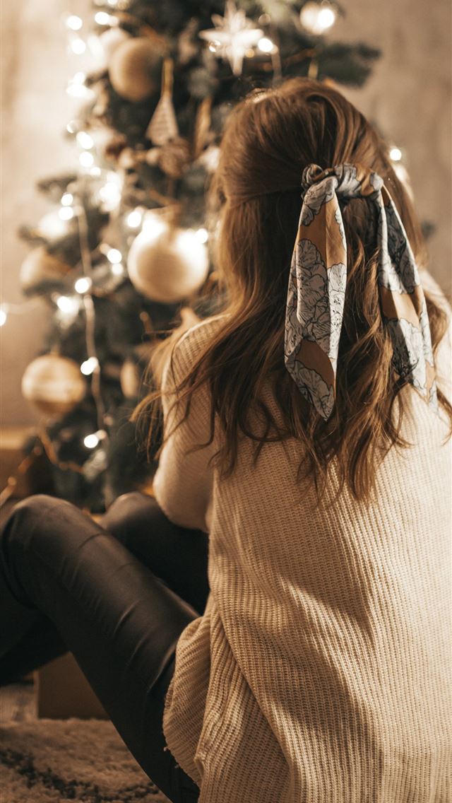 1290x2796 woman sitting near Christmas tree -  iphone 15 Wallpaper