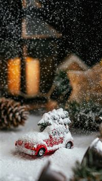 a toy car covered in snow next to a christmas tree wallpaper