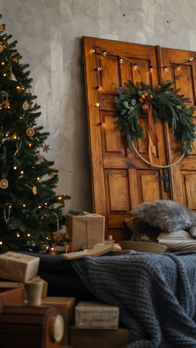 1290x2796 a christmas tree and presents under a wooden door -  iPhone Wallpaper