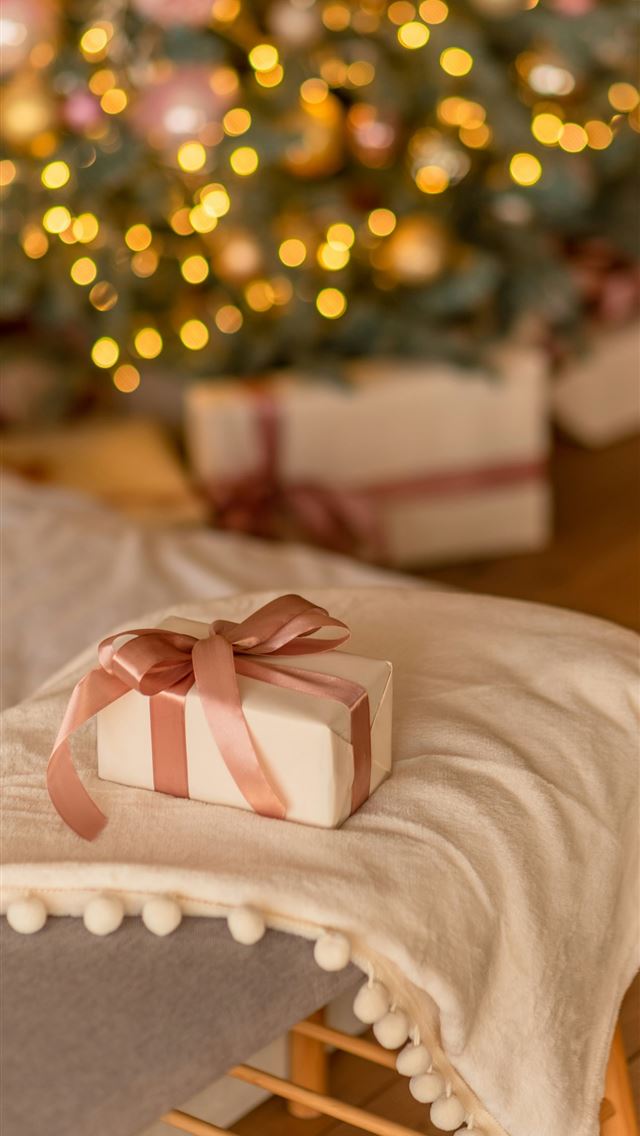 1290x2796 a present sitting on a bed with a christmas tree i... - christmas iPhone Wallpaper