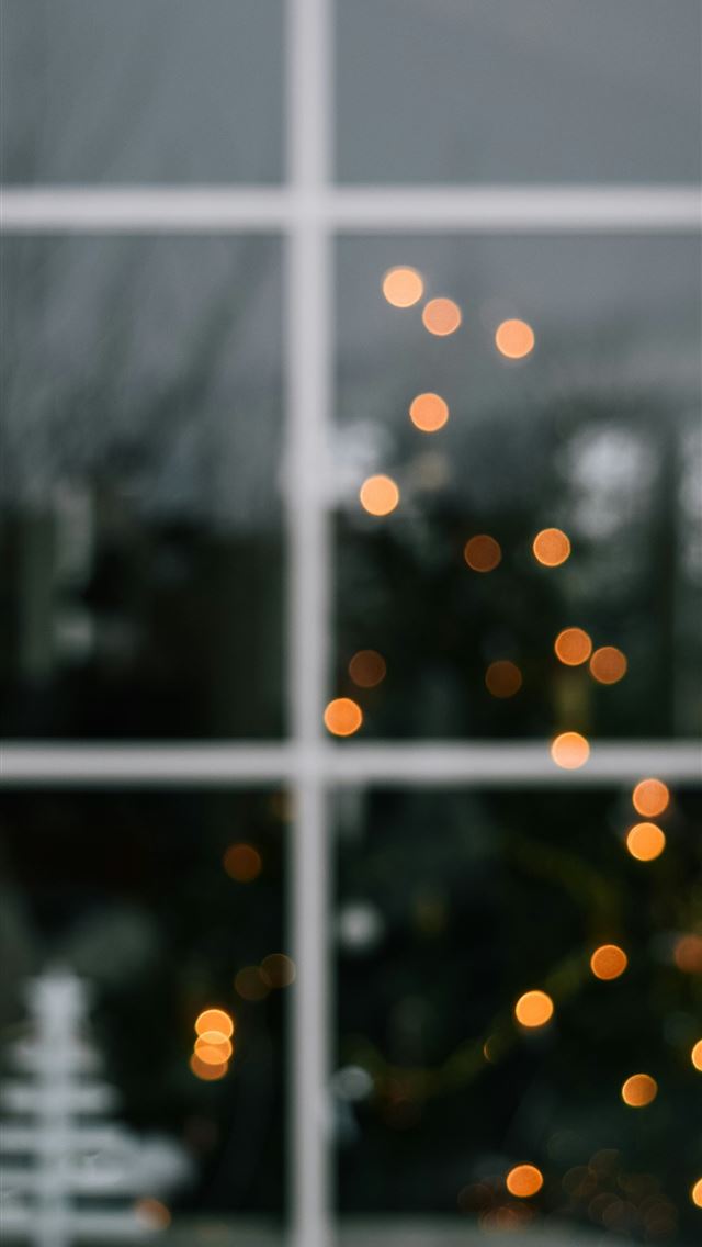 1290x2796 a christmas tree is seen through a window -  iPhone Wallpaper