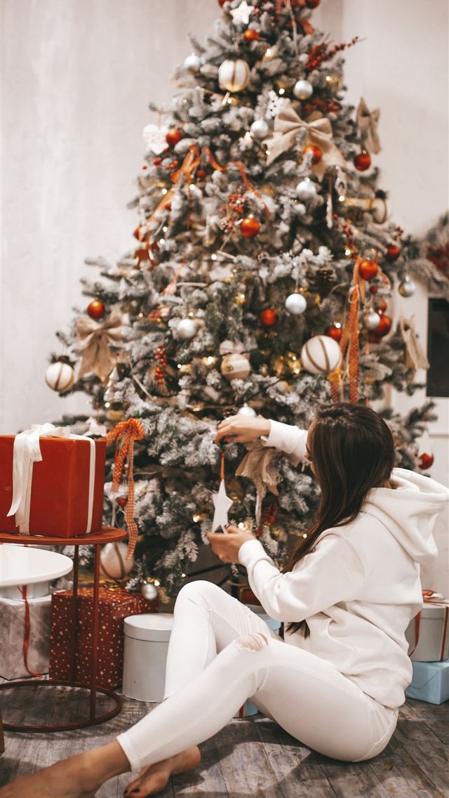 1290x2796 woman putting decors on Christmas tree -  iPhone Wallpaper
