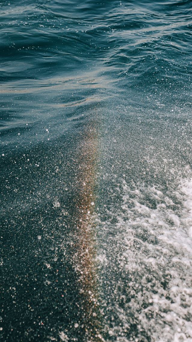 1290x2796 A rainbow is seen in the water from a boat -  iPhone Wallpaper