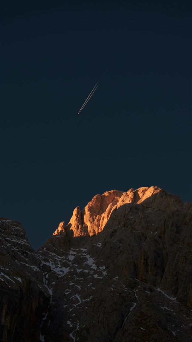 640x1136 A view of a mountain with a plane flying in the sk... -  iPhone Wallpaper