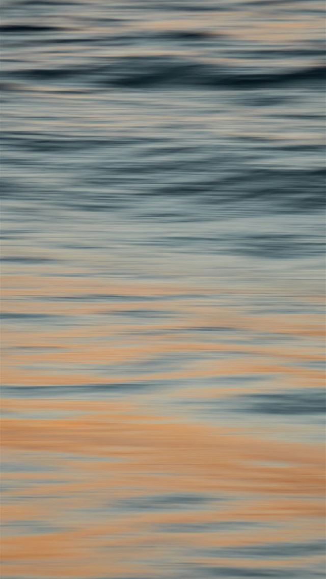 640x1136 A blurry photo of a bird flying over a body of wat... -  iPhone Wallpaper