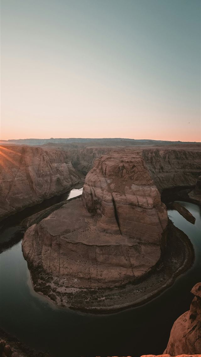 1290x2796 The sun is setting over a river in the desert -  iPhone Wallpaper