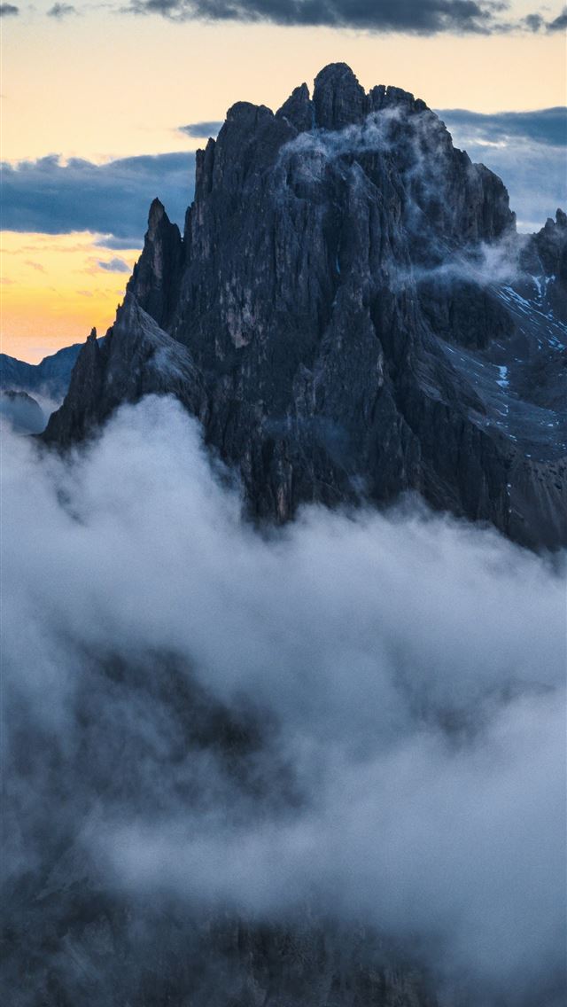 1290x2796 A mountain range covered in clouds at sunset -  iPhone Wallpaper