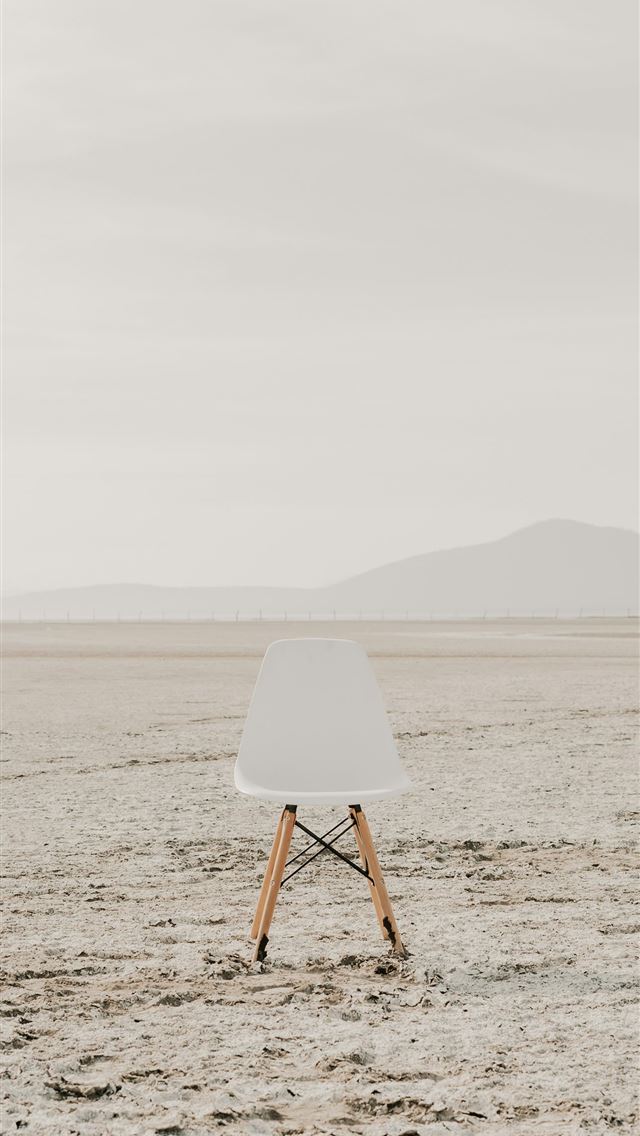 1290x2796 a white chair sitting on top of a sandy beach -  iPhone Wallpaper