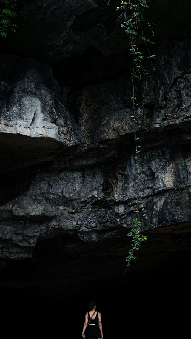 1290x2796 A person standing in front of a cave -  iPhone Wallpaper