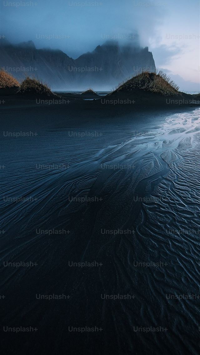 1290x2796 a beach with a mountain in the background -  iPhone Wallpaper