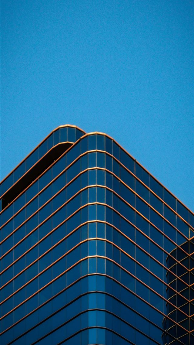 1290x2796 a plane flying in the sky over a building -  iPhone Wallpaper