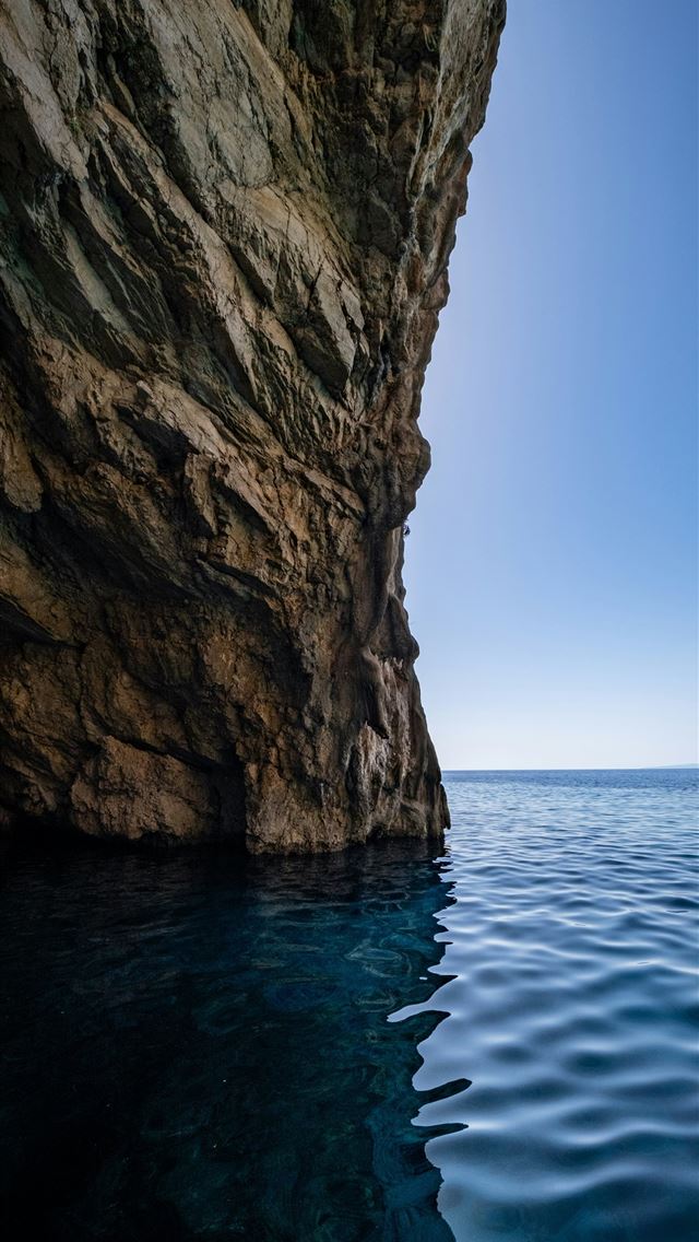 1290x2796 A large rock sticking out of a body of water -  iPhone Wallpaper