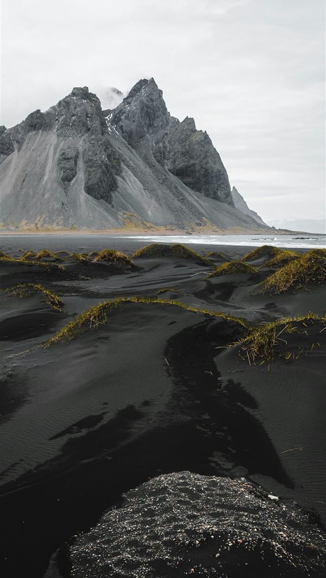 1290x2796 a black sand beach with a mountain in the backgrou... -  iPhone Wallpaper